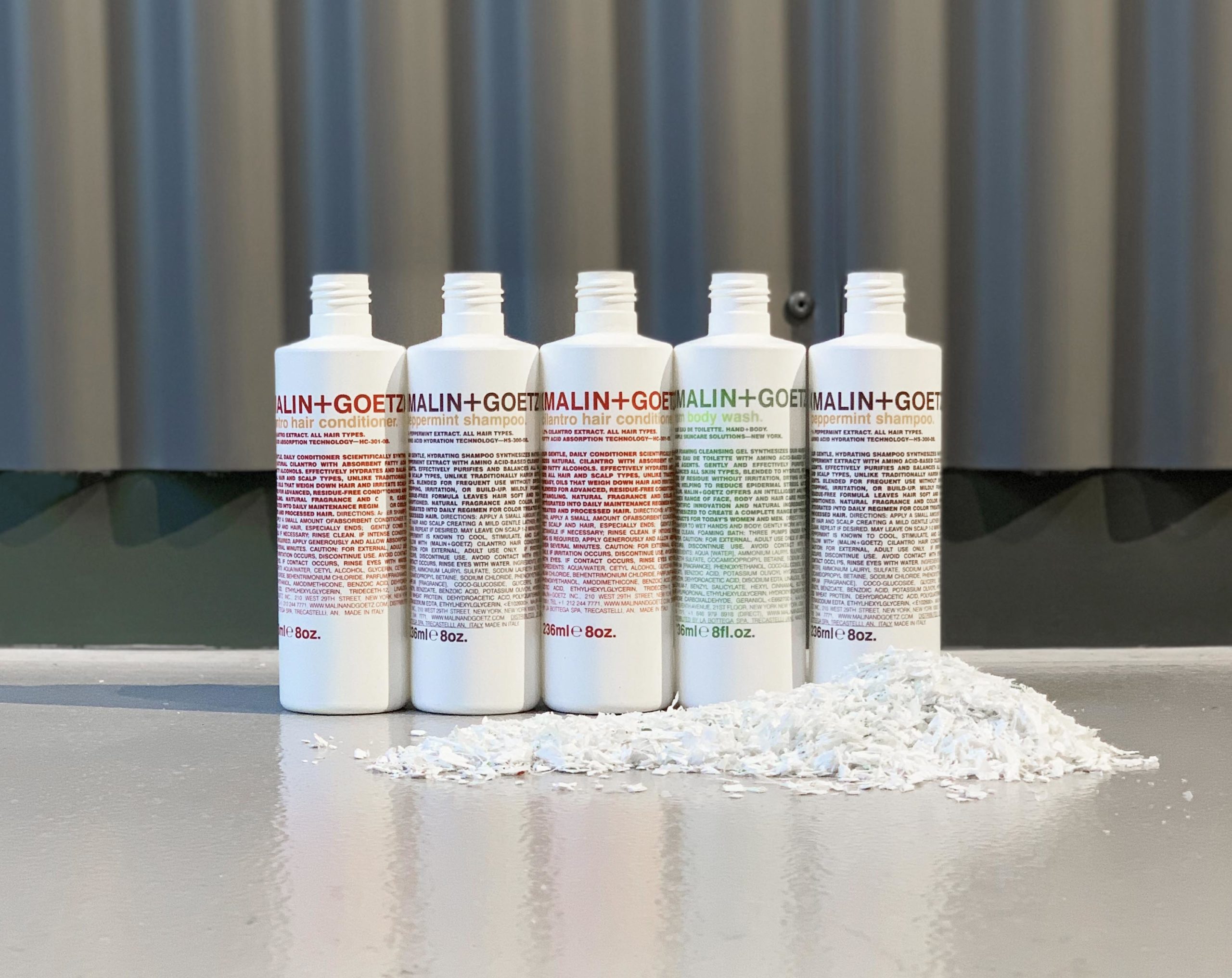 Reception desk at Room2 Belfast made from recycled shampoo and body wash bottles in a warm ombre gradient.